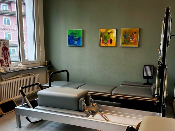 Kleines Studio mit Pilates-Reformer vor der grünen Wand